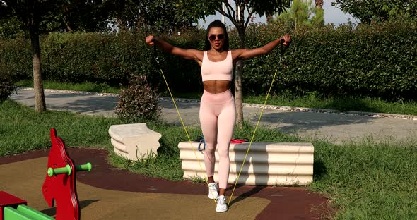 Black Athletic woman on the sports ground, training with elastic band.