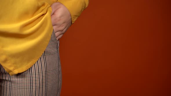 Front View on Body Part of Young Female in Yellow Blouse and Trousers on Orange Background with alt
