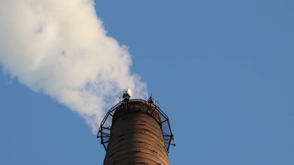 Industrial Pipe Made of Red Brick From Which There Is White Smoke