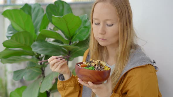 A Young Woman Enjoys Her Dinner in a Beautiful Cafe Where Poke Bowls Are Served alt
