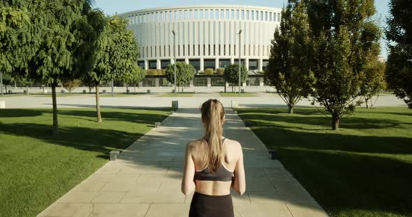 Young Sportswoman Runs in the Park at Dawn