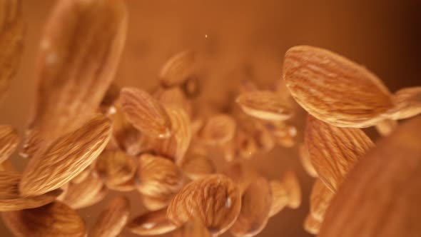 Super Slow Motion Detail Shot of Almonds Falling Down on Brown Background at 1000 Fps alt