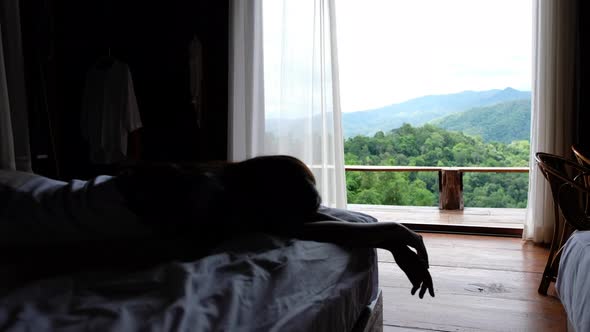 Blurred of a woman lying and sleeping on a bed with a beautiful nature view outside