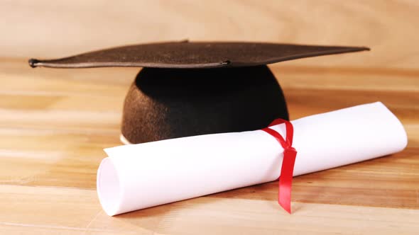 Close-up of graduation certificate with mortar board alt