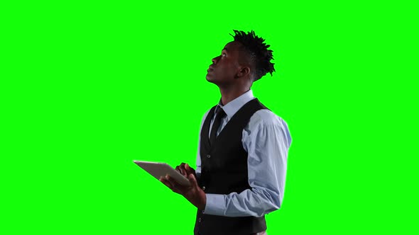 an African American man in suit using a phone in green background