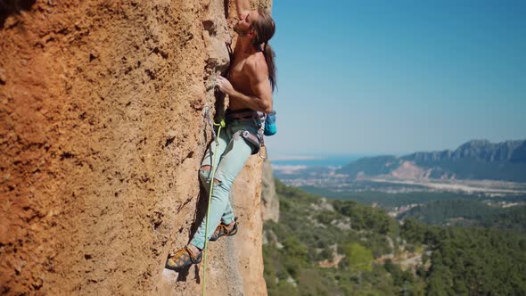 Slow Motion of Strong Man Rock Climber Climbs on Vertical Crag By Challenging Route alt