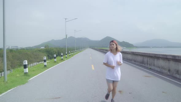Asian runner woman run and jog on street, Healthy handsome young sporty male exercise near lake.