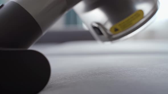 A Man with a Manual Vacuum Cleaner Cleans the Upholstery of a Sofa alt