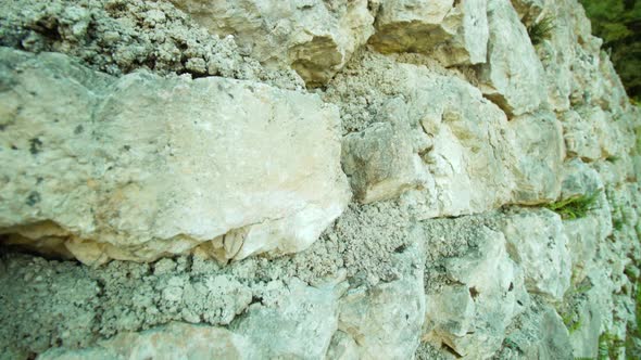 Stone Fence with White Rocks Overgrown with Moss in Park alt