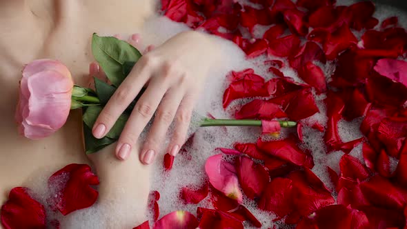 Sexy Girl Lies in a Big Stone Bath with a Rose Flower in Her Hands alt
