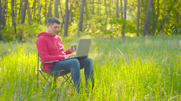 Man Working on Laptop in Summer Forest alt