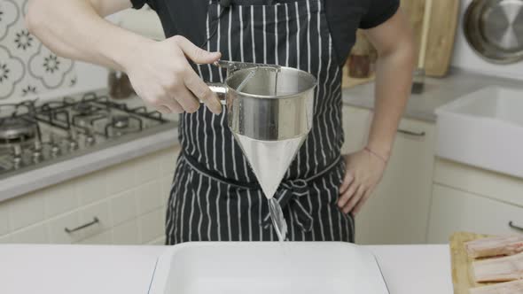 Chef pours water into cooking tray. alt