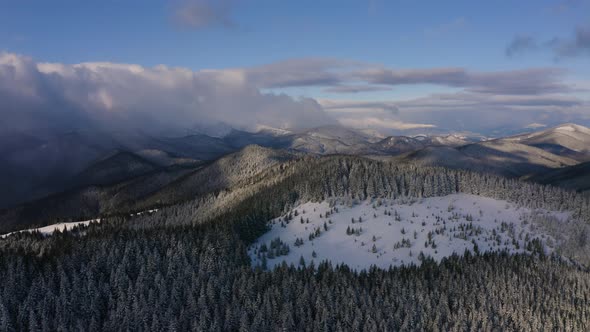Drone Aerial Flying Above Winter Snow Covered Frozen Mountains with Storm Clouds alt