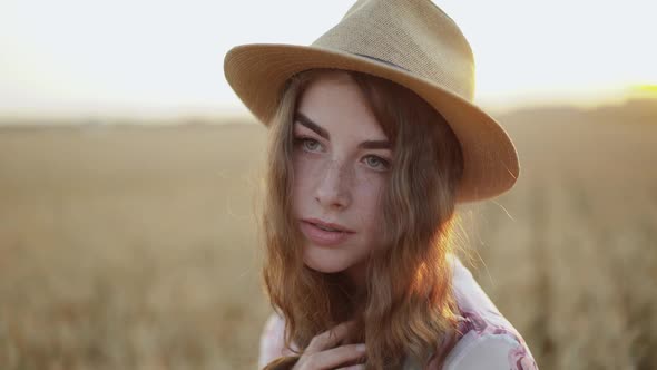 Beautiful Portrait of Dreamy Young Woman in a Hat Among a Golden Wheat Field alt