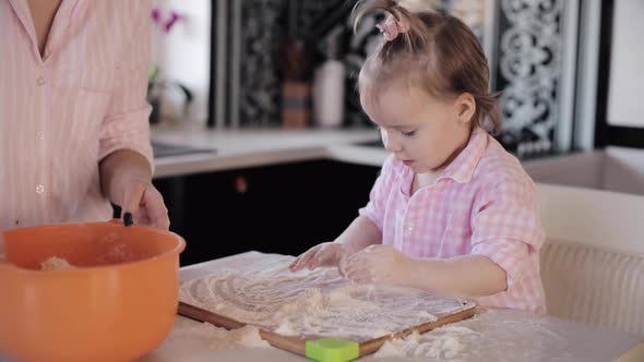 Little Girl Cooking with Caring Mother at Kitchen