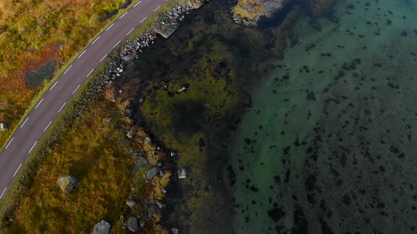Drone flying next to the street, and car is passing. Next to the shore in Norway alt