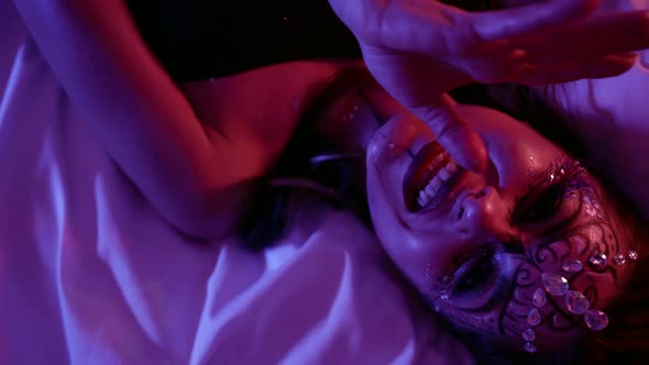 Voluptuous Woman with Scenic Makeup Is Lying on Bed and Wriggling in Extasy alt