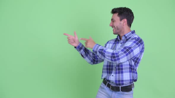 Happy Young Hispanic Man Dancing While Showing Something alt