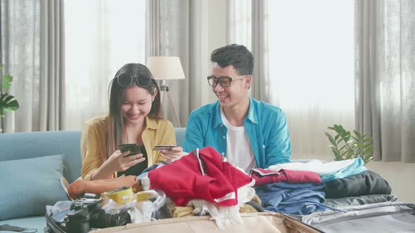 Asian Couple Booking On Smartphone With Credit Card For A New Journey. Luggage For Travel Holidays alt