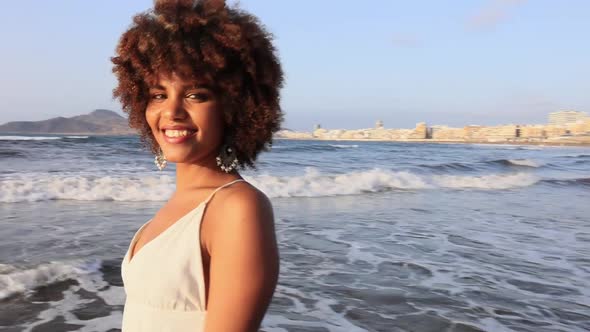 beautiful young African woman smiling happily with white dress and beach background.