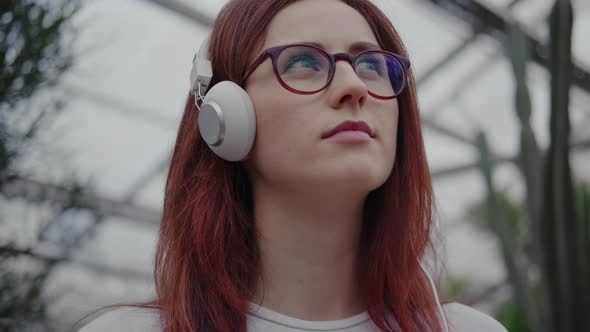 Woman in Headphones and Glasses, She Listens To Music and Looks Up
