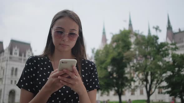 Girl with Cell Near Hungarian Parliament Building in Budapest alt