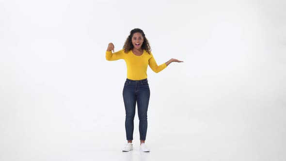 Excited young African American woman pointing down finger to empty space