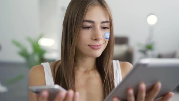 Portrait of Young Attractive Woman with Painted Message Box on Her Face Holding Phone and Tablet In alt