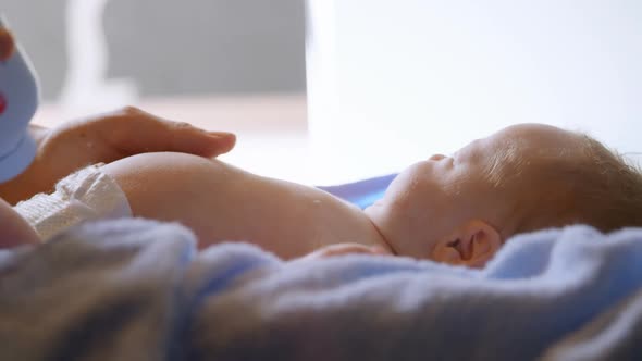 Mother applying powder to her baby boy at home 4k alt