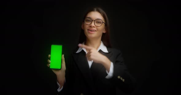 Business Lady in Glasses Shows Vertical Green Phone Screen for Copying alt