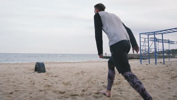 Young Man Doing Parkour Tricks on the Beach Near the Sea alt