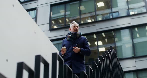 A Man with a Cup of Coffee Descends the Stairs Near the Modern Office Center alt