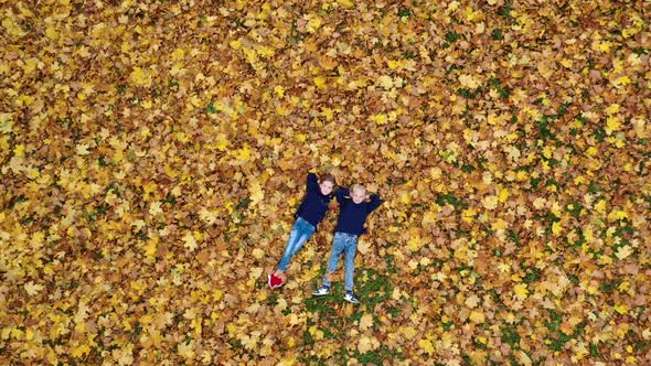 Aerial viev Happy Children Lying On Autumn Fallen Leaves in the Park.