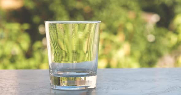 Pouring Fresh Pure Water Into a Glass in The Garden