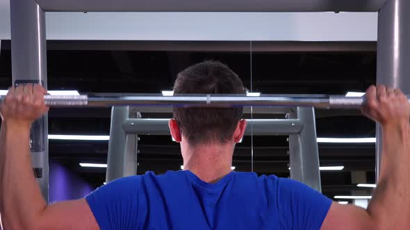 A Young Fit Man Does Overhead Presses in a Gym - Closeup From Behind alt