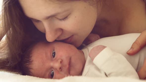 Newborn baby boy and his mother at home. Close-up portrait of the infant alt