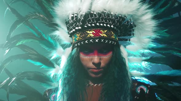 Beautiful Girl in Native American Indian Headdress and Costume with Colorful Makeup Makes Movements alt