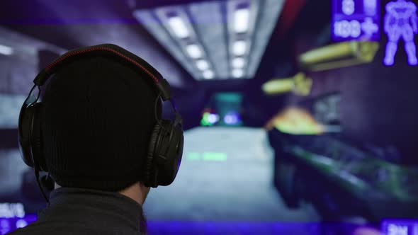 Caucasian Man in Black Hat and Headste Playing in Futuristic Fist Person Shooter Game