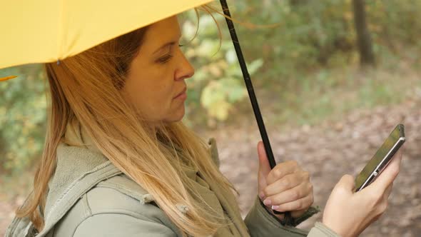 Female on mobile phone while holding yellow umbrella outdoor 4K 2160p 30fps UltraHD footage - Surfin alt