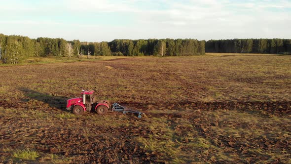 Red tractor raises a plow alt