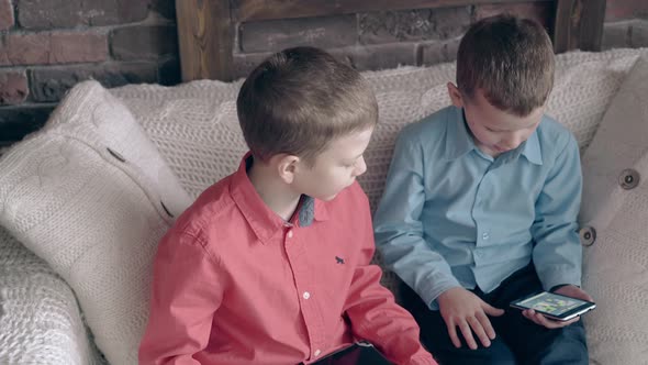 Boy Watches Little Brother Playing Games on Smartphone alt