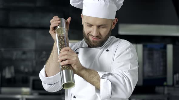 Chef Man Cooking at Kitchen Restaurant. Male Chef Peppering Food at Kitchen alt
