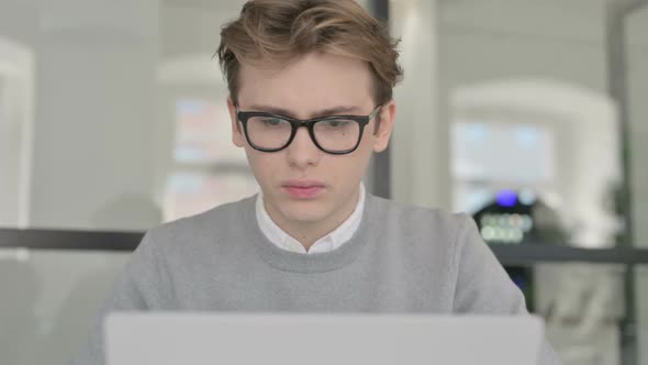 Close Up of Young Man with Laptop Showing Thumbs Down Sign alt
