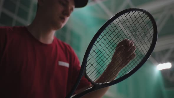 Professional Male Tennis Player is Checking His Racquet Indoor Tennis Court Before Match or Training alt