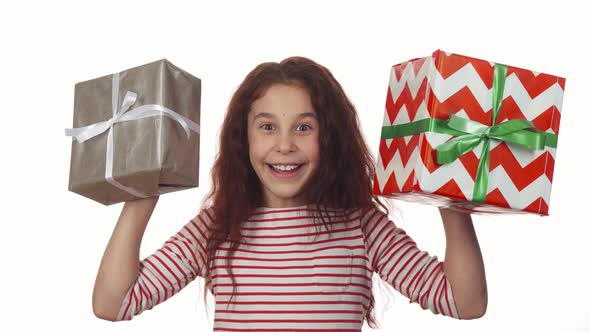 Happy Girl Holding Two Christmas Gifts in Her Hands alt