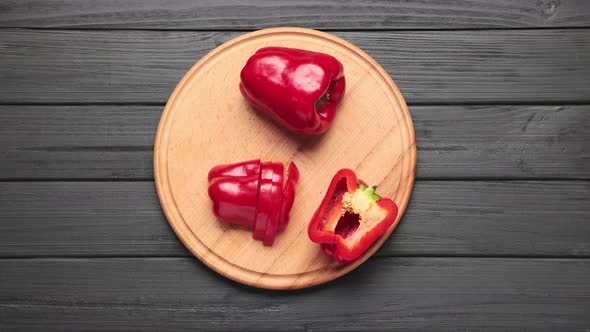 Cutting board and fresh pepper vegetables appear on dark kitchen table alt