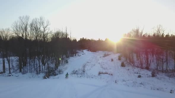 Aerial View of Snowmobile Traveling over Trail as Sun Sets