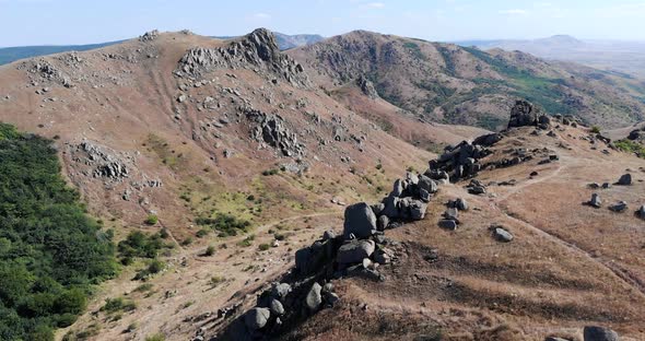 Aerial View Of Macin Mountain Range With Crag On Steep Slope On A Sunny Day alt