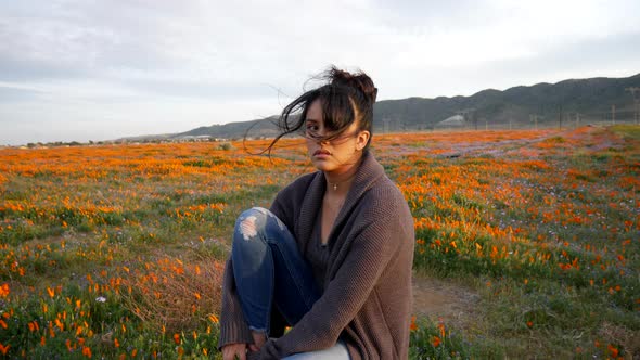 A beautiful young woman crying and looking heartbroken and depressed sitting alone in a rural field alt