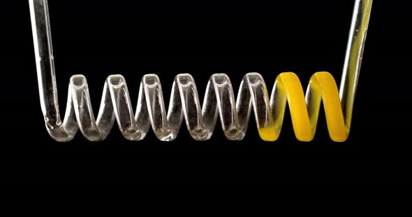 The Yellow Liquid Fills the Spiral of Glass on a Black Background in Slow Motion. Chemical Capacitor alt